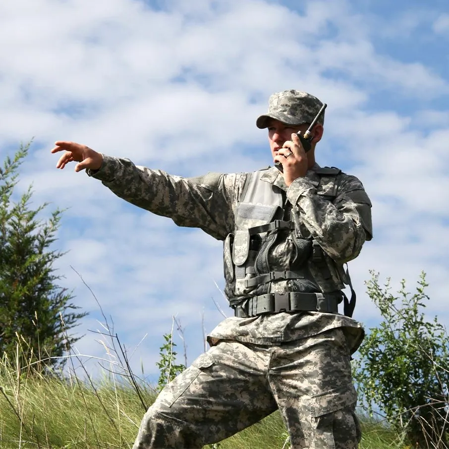 A picture of a soldier talking on a radio and pointing