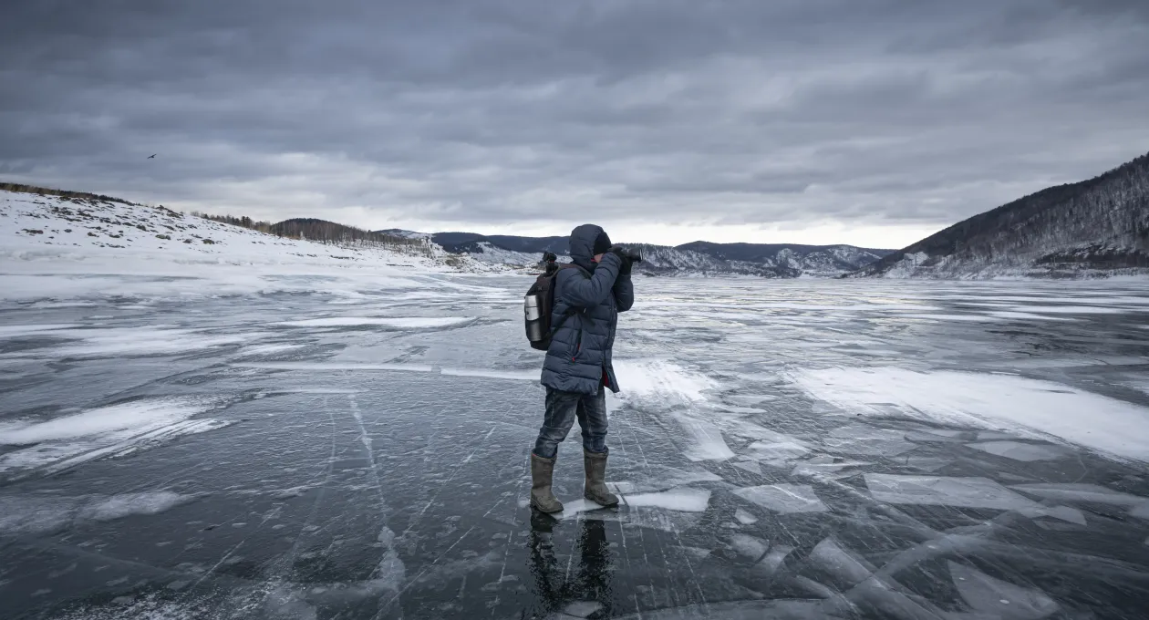 A lone adventurer captures the icy landscape on a frozen lake, embracing the solitude and tranquility of the wilderness