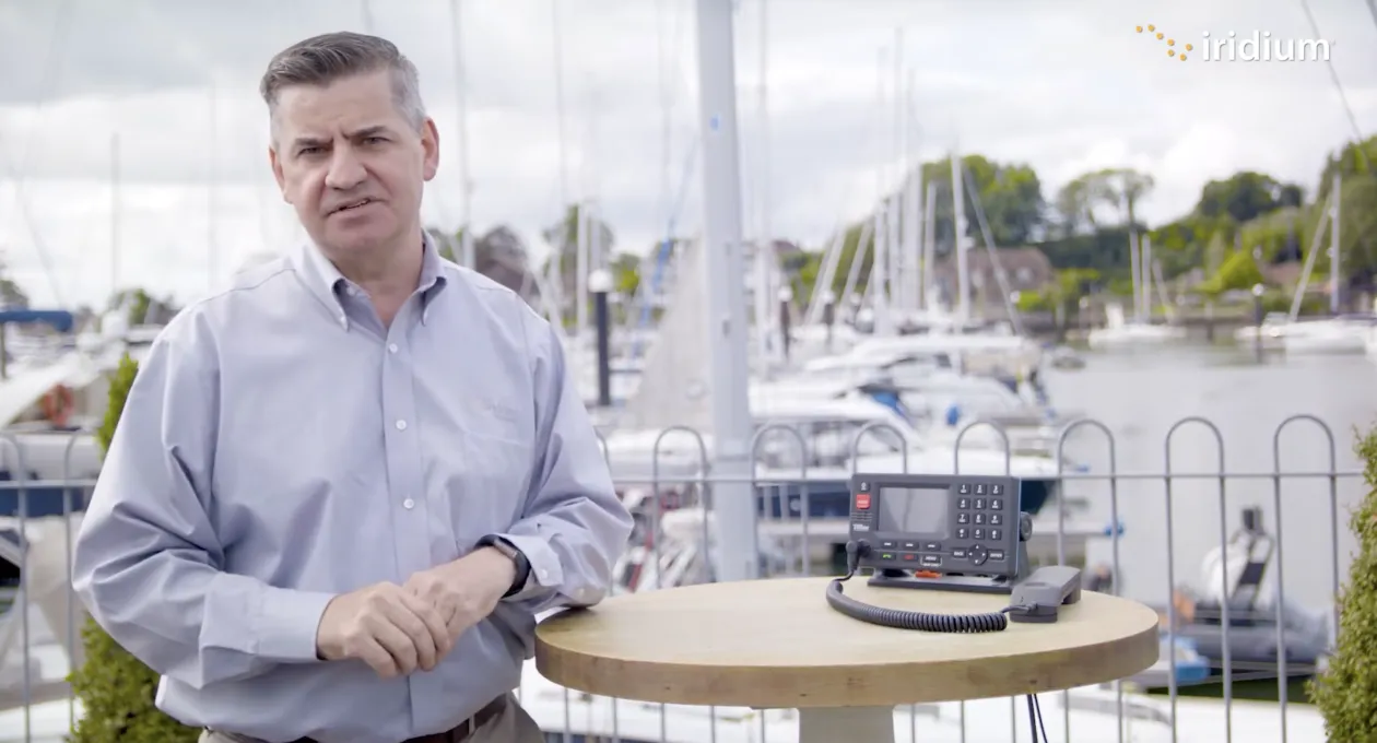 Man stands in a marina, next to a satellite phone