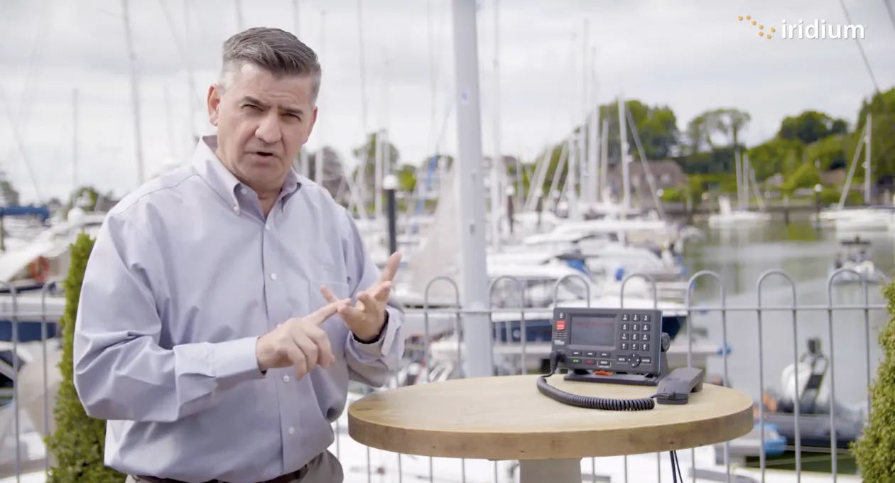 Man stands in a marina, next to satellite phone