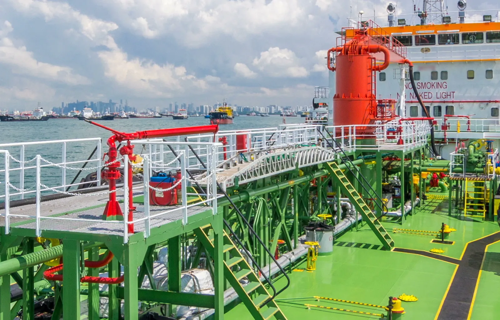 SINGAPORE - CIRCA JUNE 2018: Green deck of the tanker under blue cloudy sky timelapse. Crane with pipe mooving on it by operator