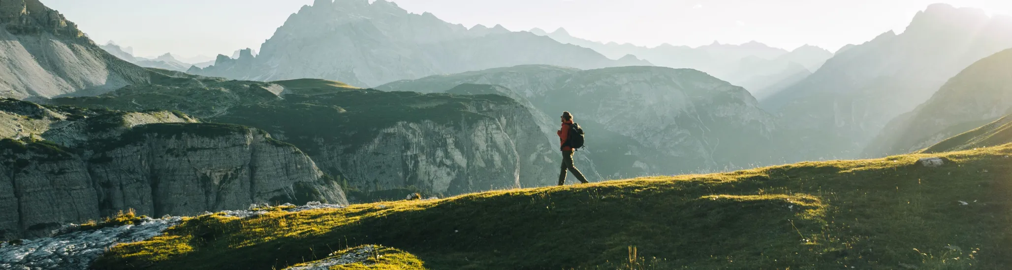Male hiker walks along mountain ridge crest, in distance