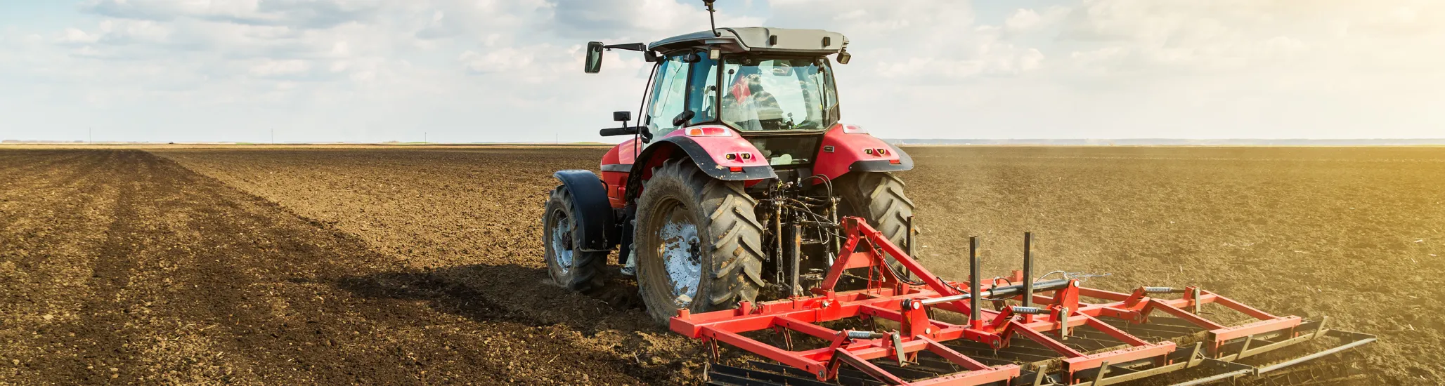 Farmer in tractor preparing land with seedbed cultivator as part of pre seeding activities in early spring season of agricultural works at farmlands.