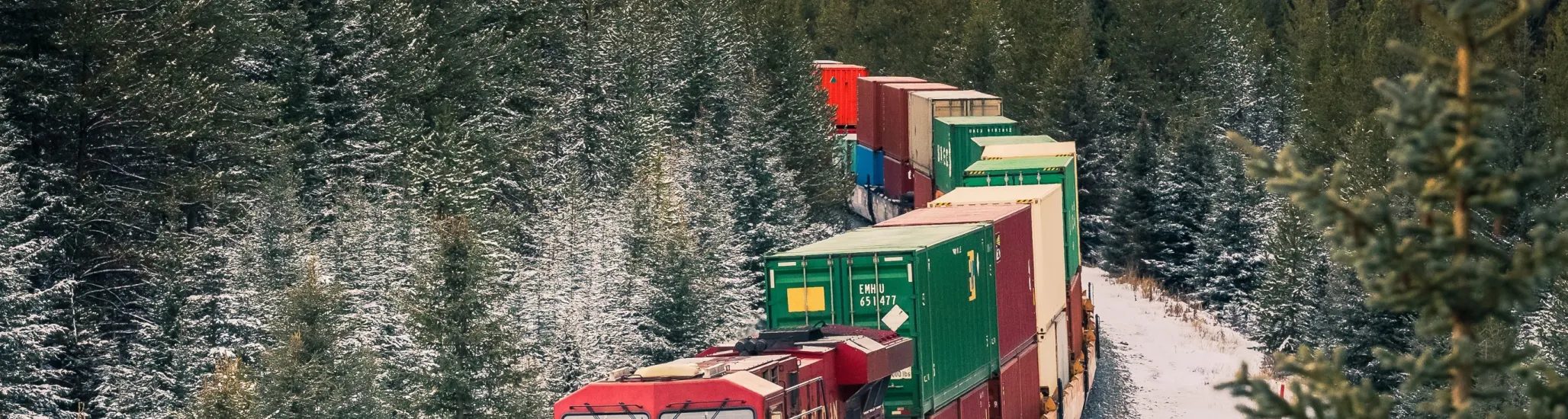 A freight train hauls shipping containers through the mountainous landscape.