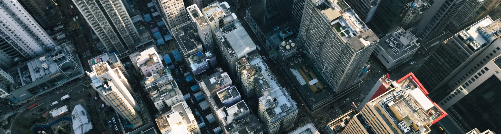 An aerial view of a dense urban skyline in Hong Kong with skyscrapers and streets below.