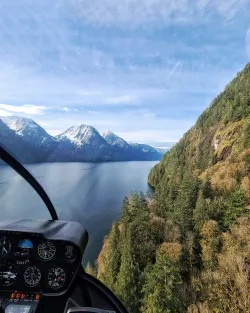 View of a lake and mountains from a helicopter cockpit