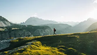 Male hiker walks along mountain ridge crest, in distance
