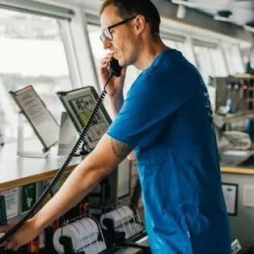 Man using GMDSS device for communications while navigating a boat