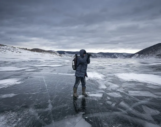 A lone adventurer captures the icy landscape on a frozen lake, embracing the solitude and tranquility of the wilderness