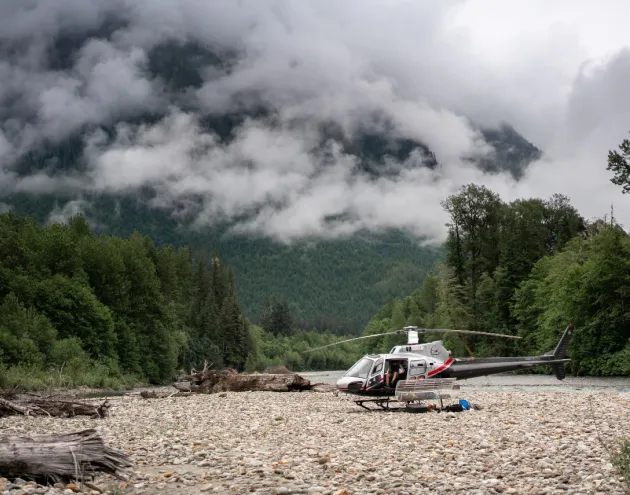 Helicopter on the ground, beautiful cloud covered mountains in the background