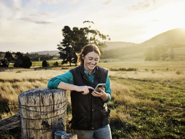 Young female farmer staying in touch via mobile technology from her farm in rural Tasmania, Australia.