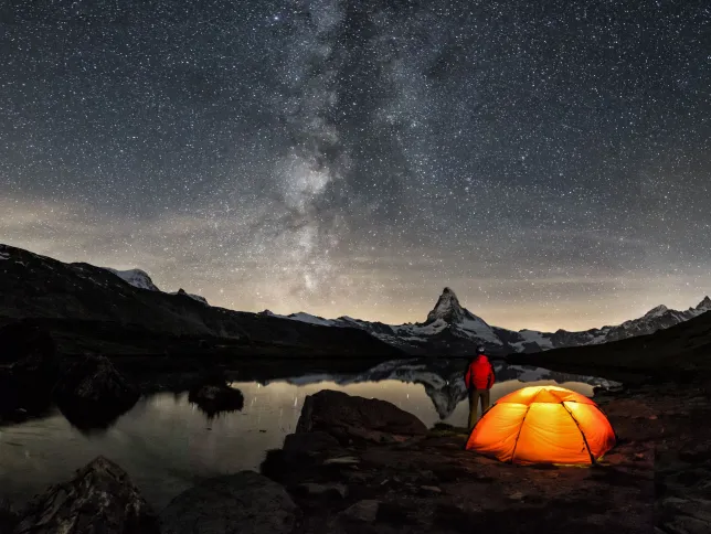An illuminated tent under Milky Way at Matterhorn in Switzerland
