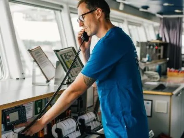 Man using GMDSS device for communications while navigating a boat