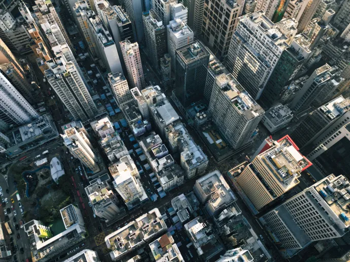 An aerial view of a dense urban skyline in Hong Kong with skyscrapers and streets below.