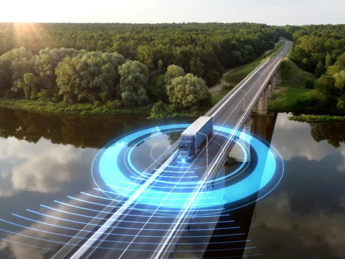 Autonomous semi-truck with a trailer, controlled by artificial intelligence, drives over a bridge over the river. Cargo delivery, transportation of the future. Artificial intelligence. Self driving.