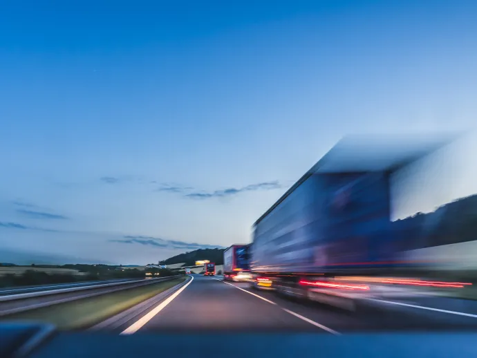 Background photograph of a highway. Truck on a motorway, motion blur, light trails. Evening or night shot of trucks doing logistics and transportation on a highway.