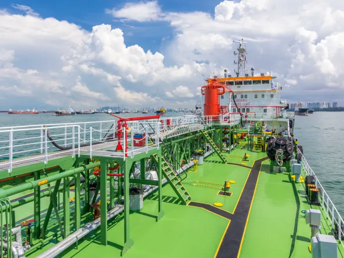 SINGAPORE - CIRCA JUNE 2018: Green deck of the tanker under blue cloudy sky timelapse. Crane with pipe mooving on it by operator