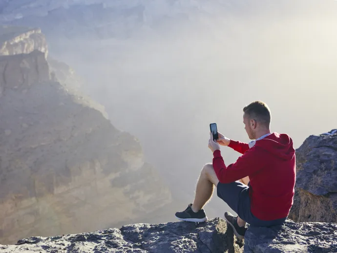 Relaxation in mountains. Young man photographing by mobile phone. Jebel Akhdar, Grand Canyon of Oman.