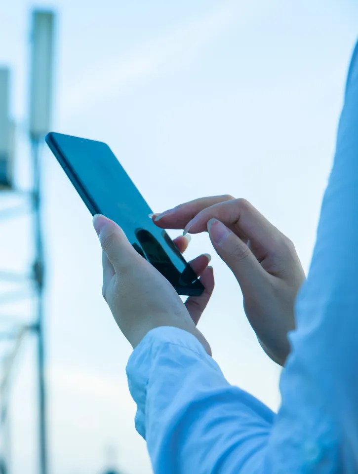 Human hand using mobile phone near 4G,5G communications tower