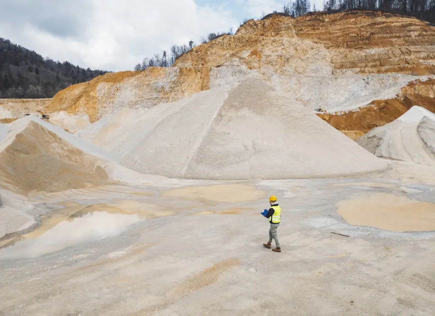 Open pit quarry, aerial photo. Making of gravel from quarry rocks. Heavy machinery working on quarry grounds, transporting gravel with trucks. Construction material