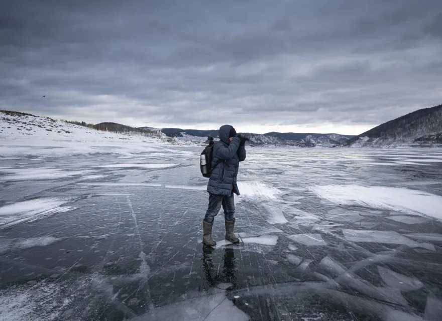 A lone adventurer captures the icy landscape on a frozen lake, embracing the solitude and tranquility of the wilderness