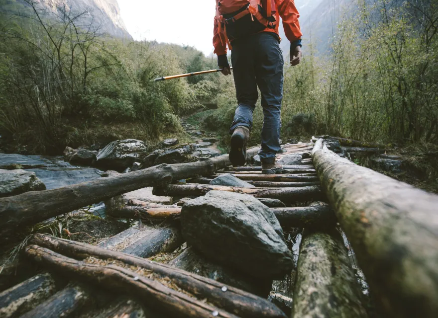 Cropped shot of mountain trekker crossing the bridge in region of Annapurna, Himalayas.