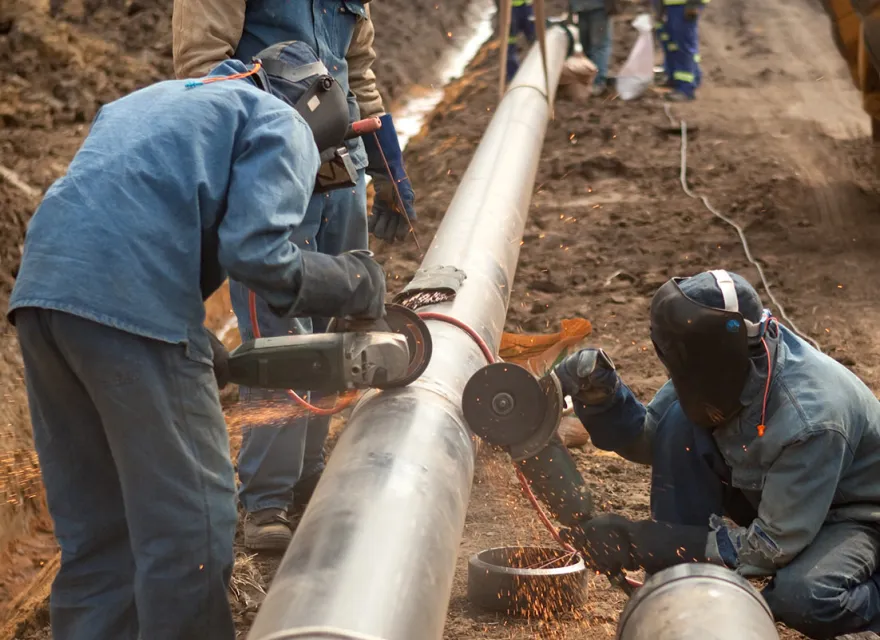 Workers in the field, cutting a gas pipeline