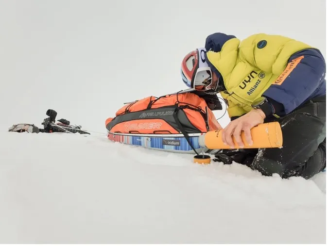 Ultra cyclist Omar Di Felice kneeling in the snow beside his sled and expedition gear during his Antarctica ride.