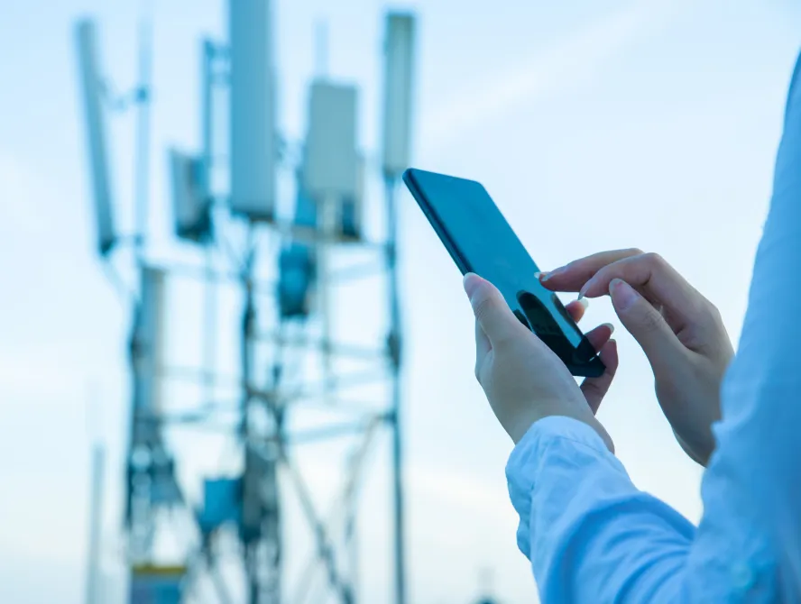 Human hand using mobile phone near 4G,5G communications tower