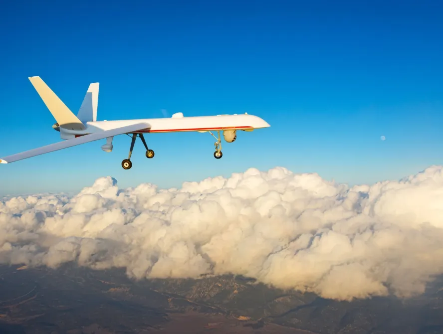 Combat drone flies high in the sky sunset clouds. Modern warfare and drones spy