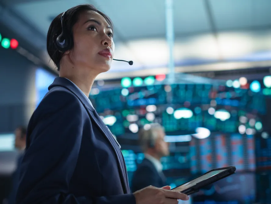 Young Asian Female Broker Working on Tablet Computer on Stock Exchange Floor