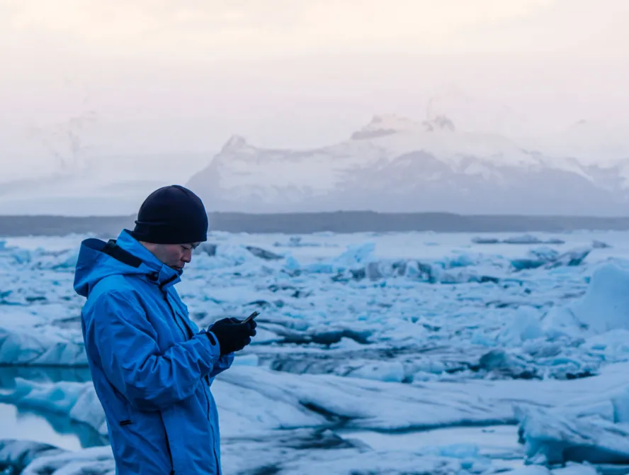 Asian man using smart phone at jokulsarlon, Glacier lagoon Iceland.  World travel destination