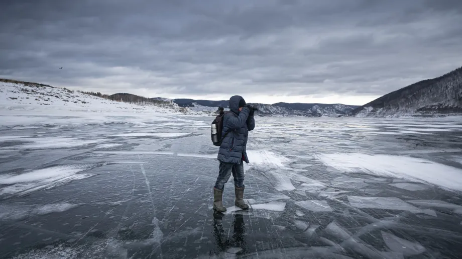 A lone adventurer captures the icy landscape on a frozen lake, embracing the solitude and tranquility of the wilderness