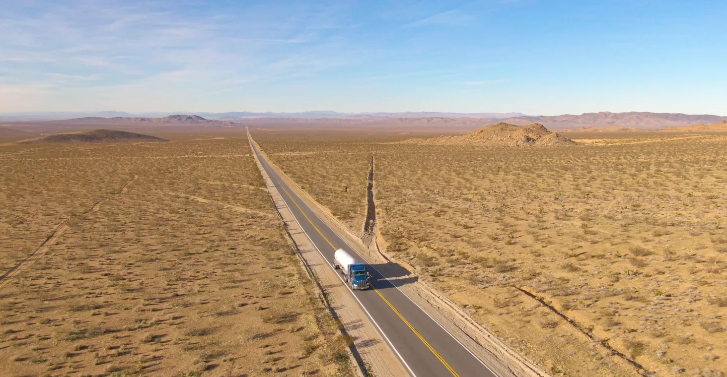 Big rig hauls a cistern across the rugged Mojave desert on a sunny day