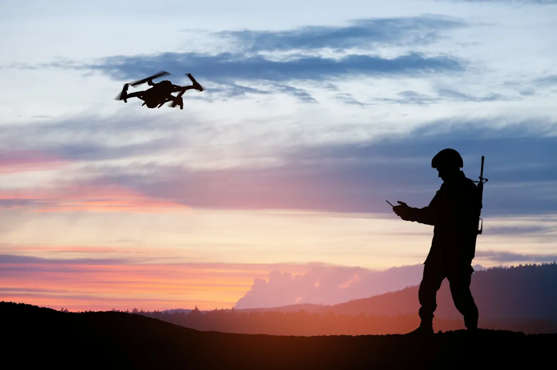 Silhouette of soldier operating a drone at sunset