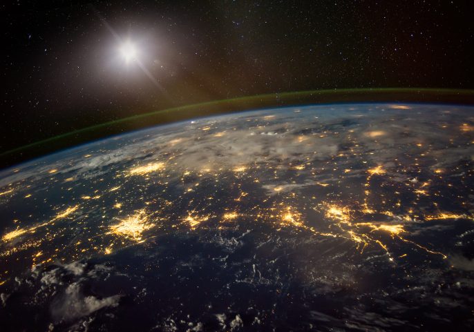 View of Earth from space with network lines connecting across continents and the sun glowing on the horizon.