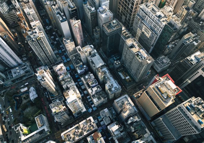 Aerial view of a dense cityscape with tall buildings and narrow streets in daylight.